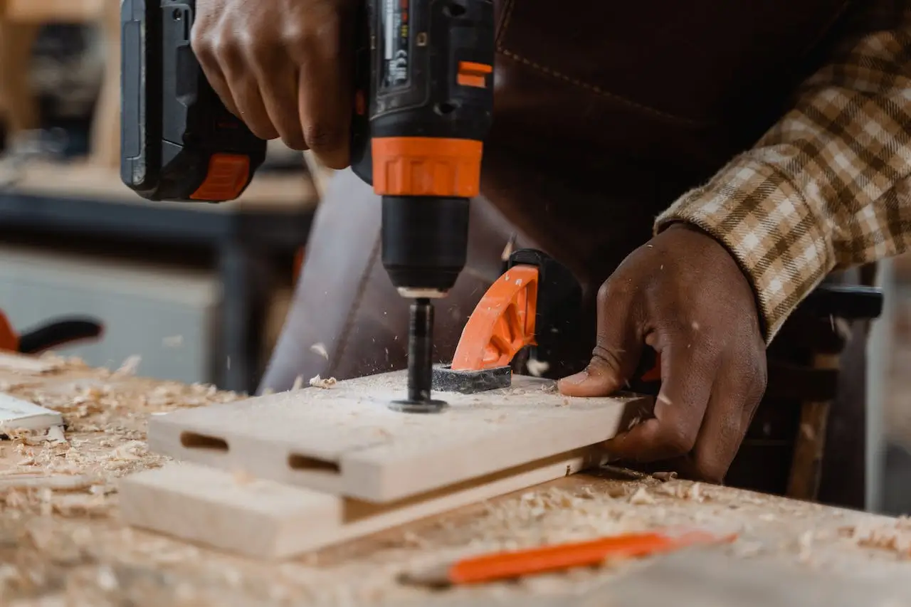 Man making a hole in a board with a drill